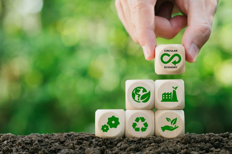 Circular economy concept.Hand holding wooden block with green bokeh background.