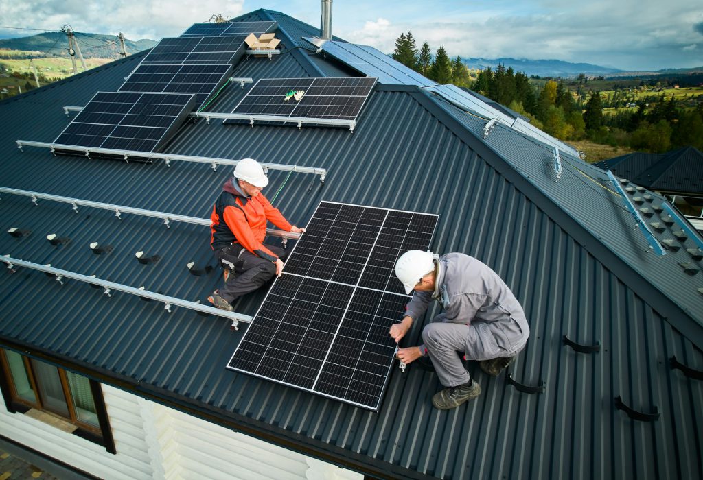 Tekniker som installerar solcellspaneler på husets tak.